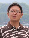 Dr. Liachun Wang posing wearing a brown and white striped polo shirt with a landscape background