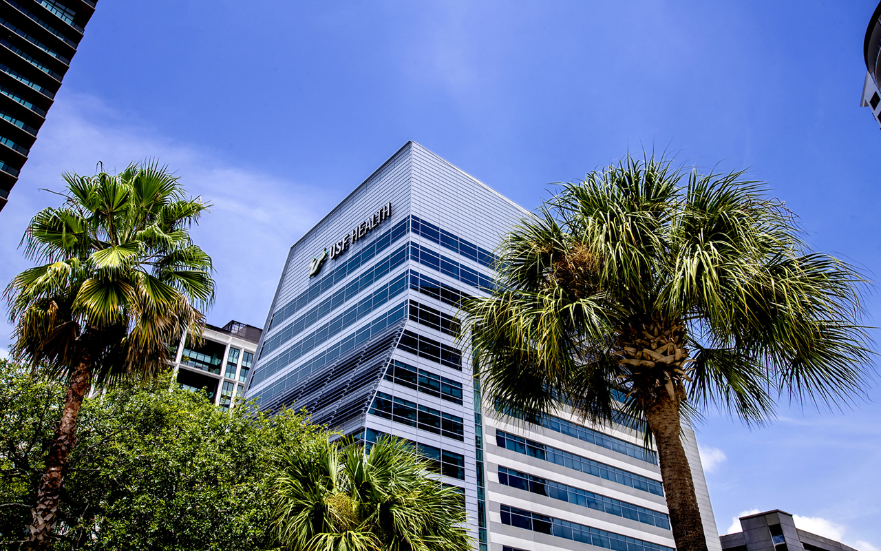 Side angle of the USF Health downtown Tampa building with palm tree landscape