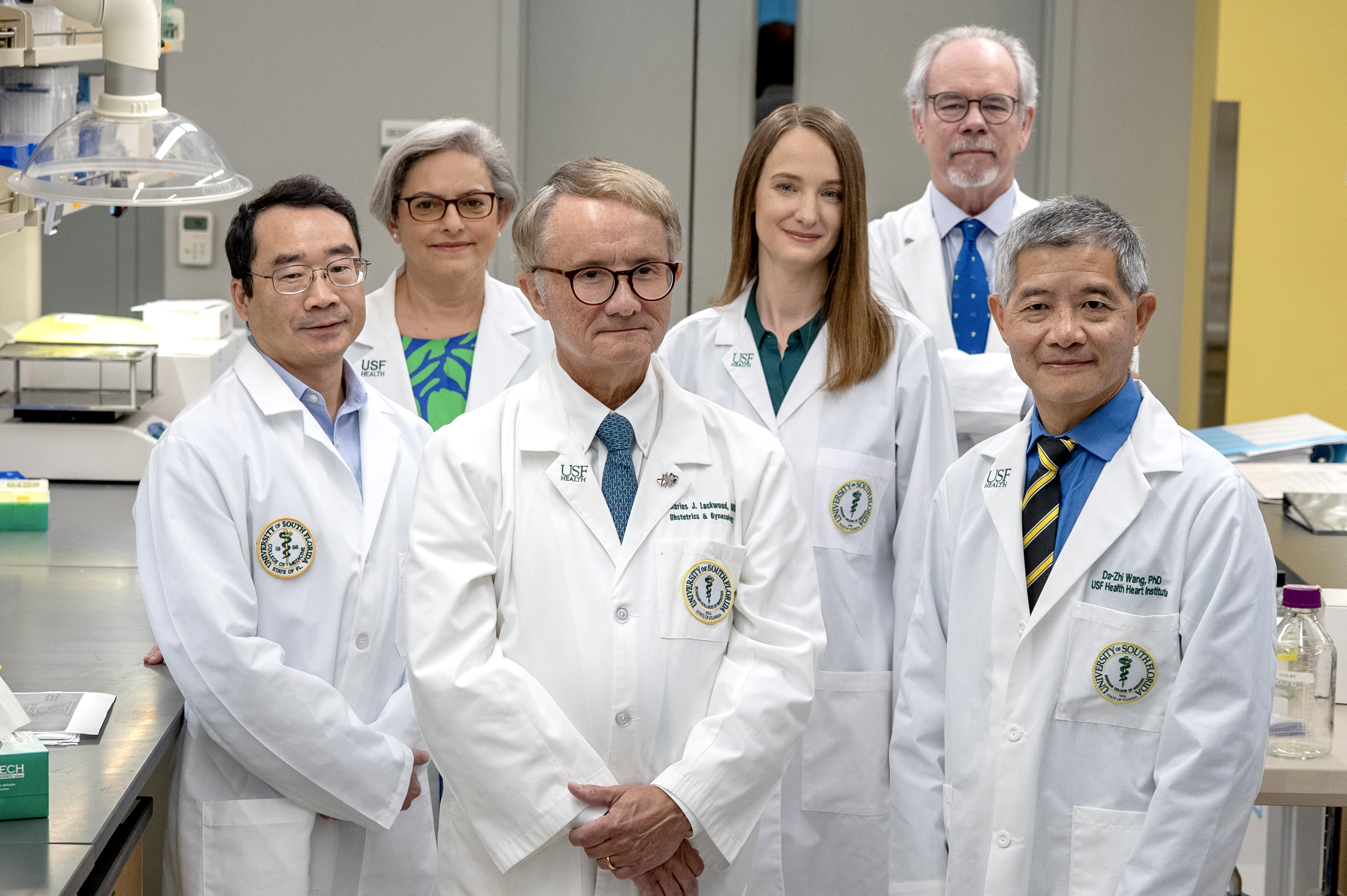 USF Health researchers standing in a lab in a group wearing medical white coats