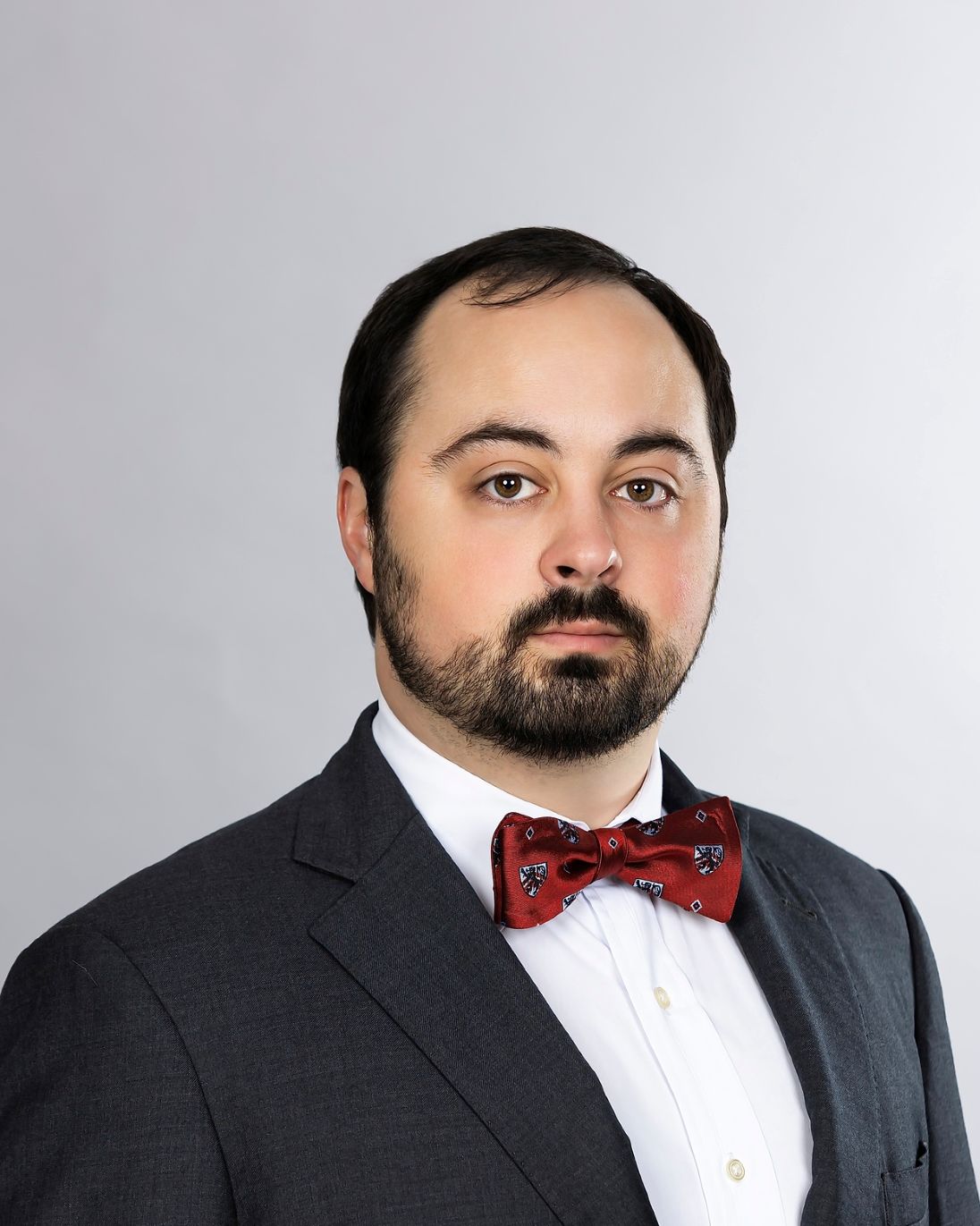 Charles Alver posing for a headshot wearing a suit with a red bow tie