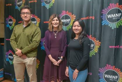 Dr. Karen Liller, Amadeo Brandon, and Truc (Jenny) Ho standing in front of a WMNF 88.5 FM backdrop.