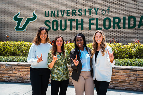 Four ASBN students showing the bull sign outside