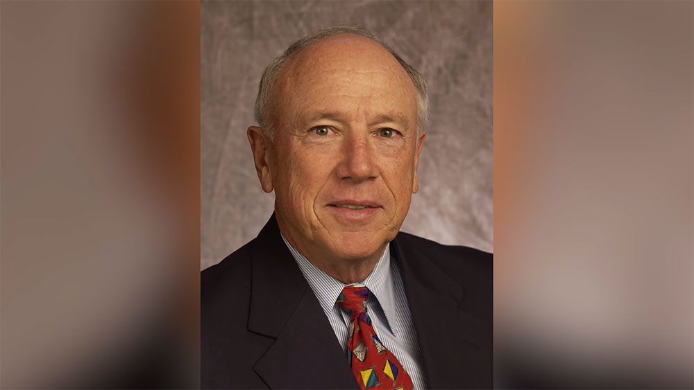 Professional portrait of Mr. Samuel P. Bell, III in a dark suit, white shirt, and red patterned tie against a neutral background.