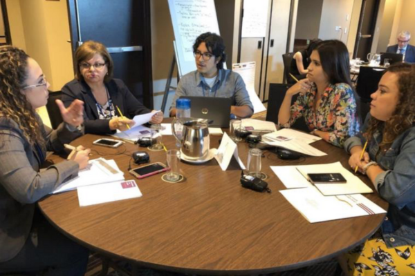 A team of people representing USF COPH social marketing, sitting at a table, focused on papers and engaged in a collaborative meeting.