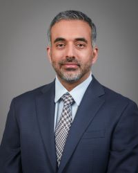 Professional Headshot of Dr. Puya Alikhani in a grey suit and tie