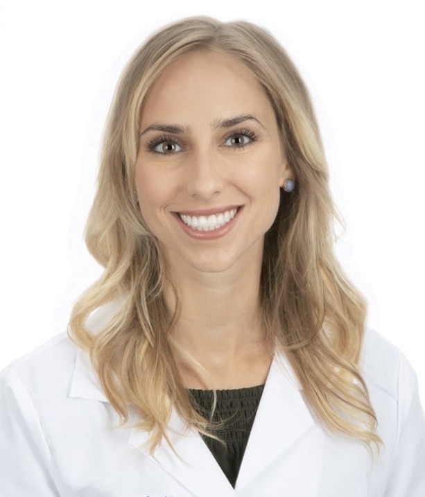 Headshot of Dr. Backen with long blonde hair, wearing a white coat and stud earrings against a white background.