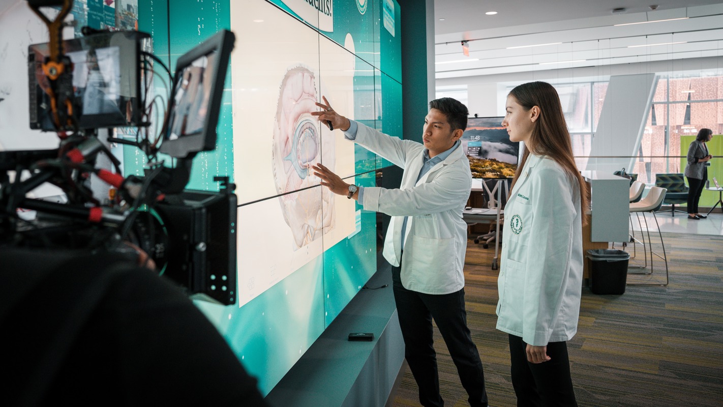 Two USF Health residents examine a digital image on an interactive screen