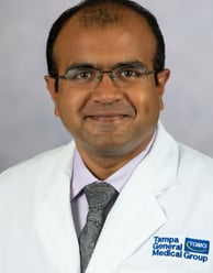 Dr. Vijay Subramanian headshot smiling with a medical white coat and shirt & tie