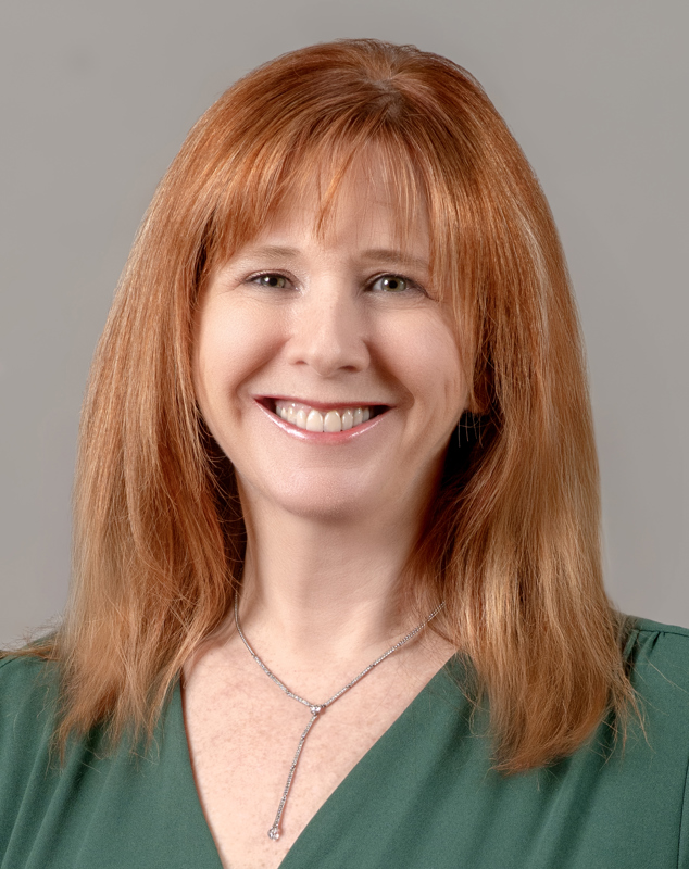 Allison Long with vibrant red hair, smiling wearing a green blouse in front of a grey backdrop