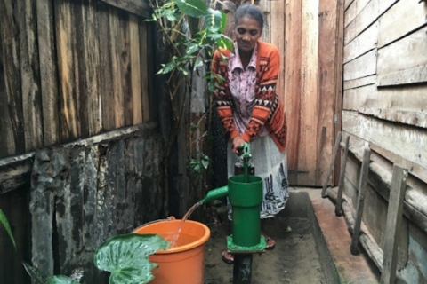 A woman standing next to a lead-free pump in Madagascar