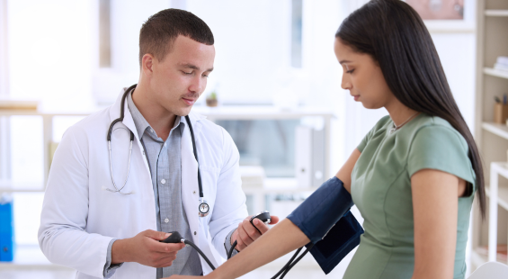 A doctor examining a pregnant patient's blood pressure.