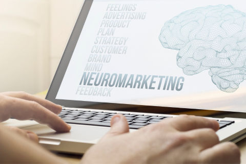 A person typing on a laptop with a screen that reads "Neuromarketing"