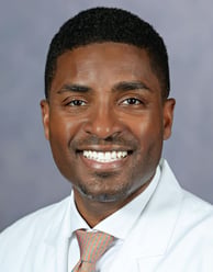 Anthony Watkins headshot smiling with a white shirt and beige tie