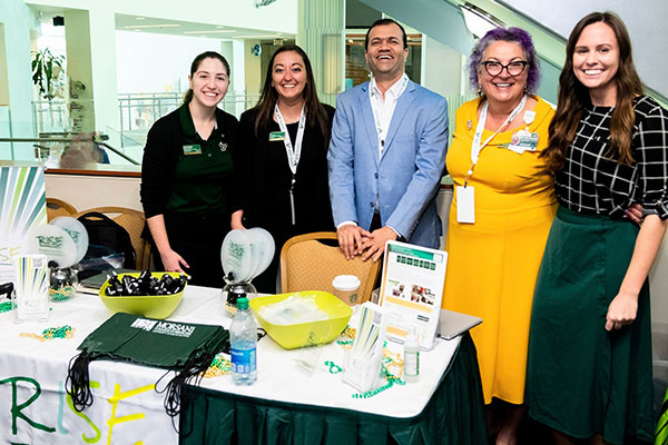 The MCOM RISE team, from left, Lynnsey Trantham, Erin May, Dr. Rahul Mhaskar, Bobby Collins, and Emily Coughlin; standing next to a RISE display table