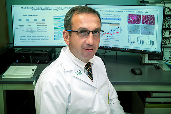 Portrait of Dr. Alexander “Sasha” Staruschenko, PhD., sitting in front of two large computer screens