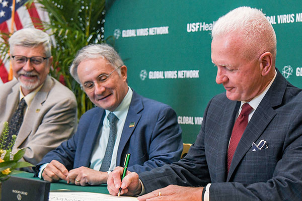 Left to right. Sten Vermund, MD, PhD, Charles Lockwood, MD, MHCM, and Brett Giroir, MD., signing a certificate at a desk