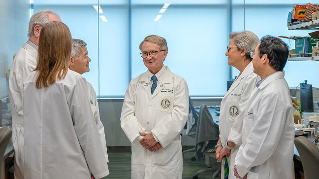A group of doctors in a medical office, wearing white coats, centered around Dr. Charlie Lockwood